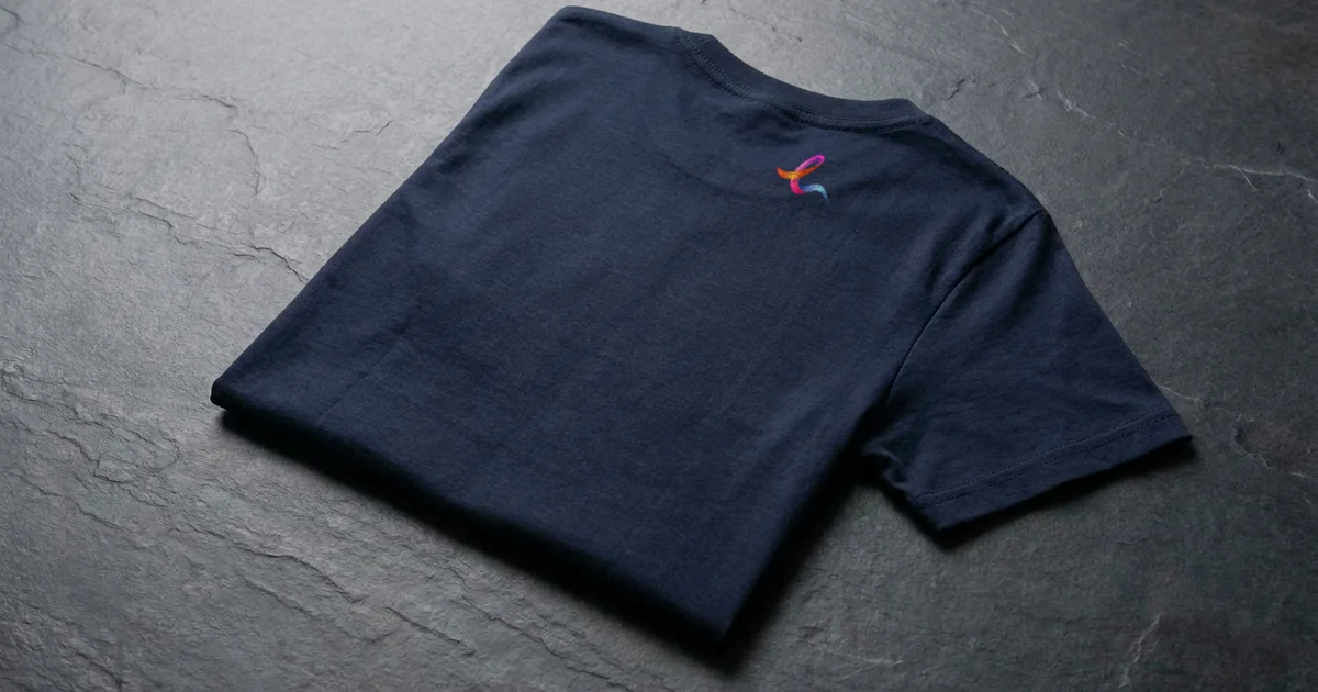Folded navy T-shirt seen from the back with a small EZ Print ribbon mark printed below the collar.